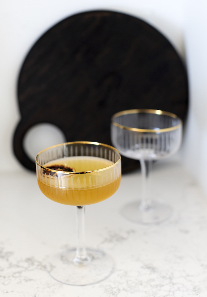 sidecar cocktail with dehydrated lemon slice garnish, white marble countertops with black cutting board